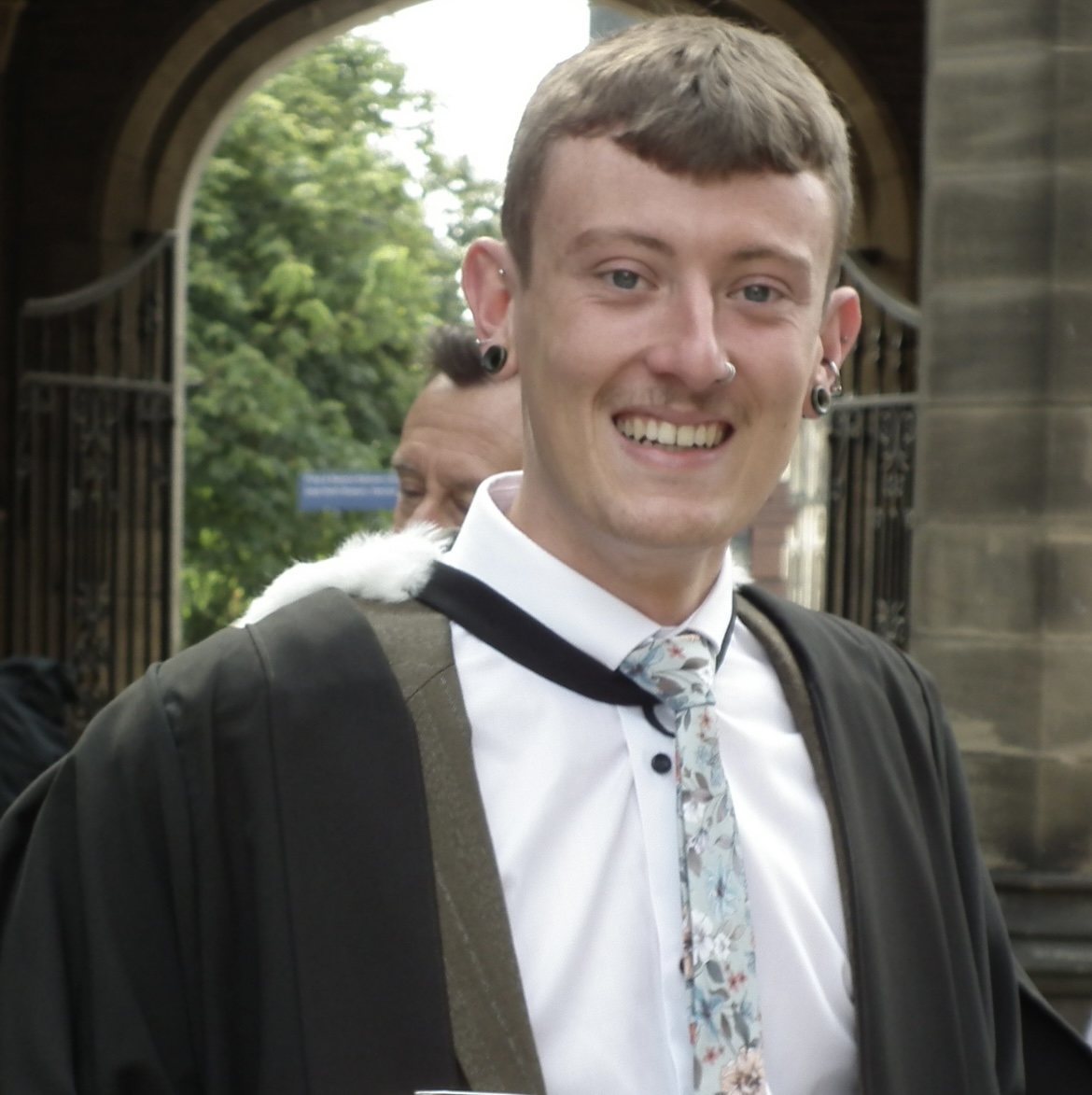 Postgraduate student smiling wearing graduation gown